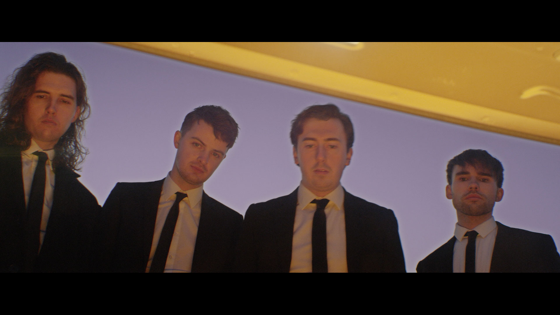 Clockworks - Video Still - The band members look into a car boot which projects a golden light onto their faces 