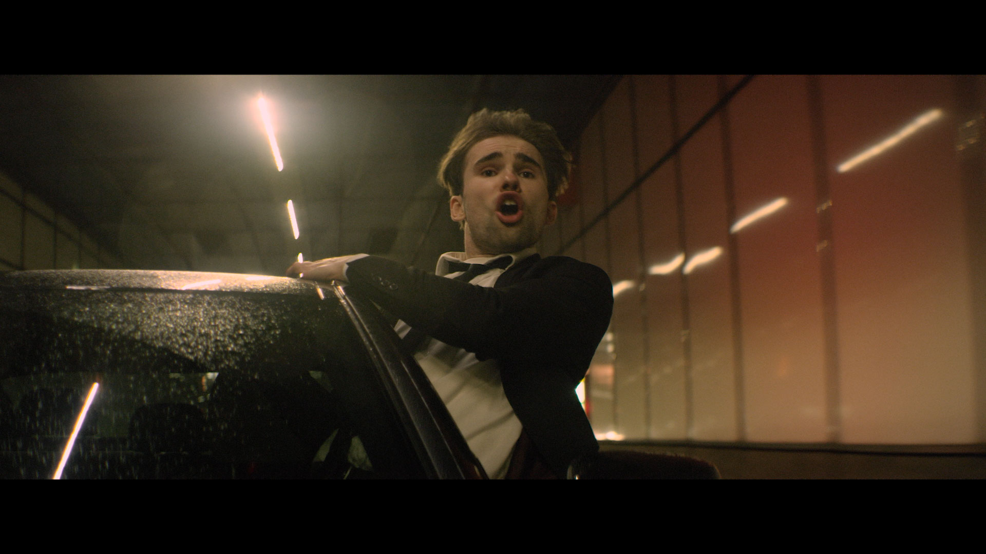 The Clockworks - "Feels So Real" music video still of lead singer hanging out of moving car window